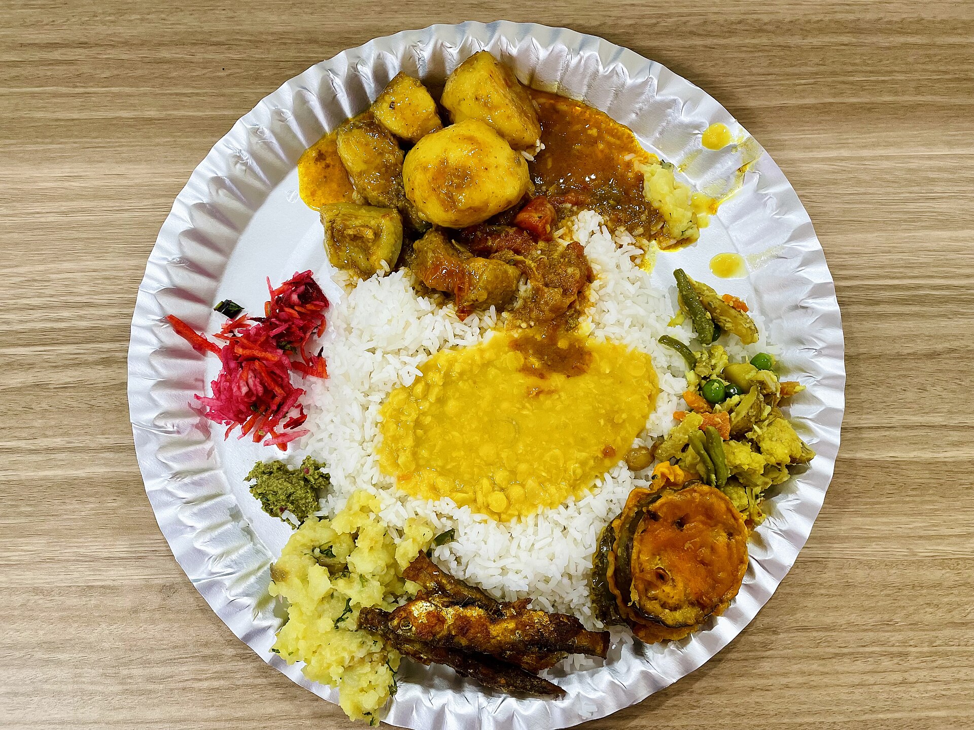 Assamese Cuisine | The India A full plate of Bengali cuisine showcases rice and a variety of curries with vegetable sides.