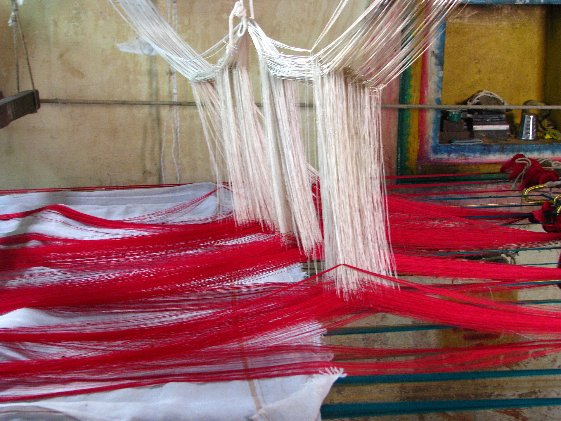 Kanjeevaram Sari | The India A traditional handloom weaves a vibrant red and white textile, showcasing Indian crafts.