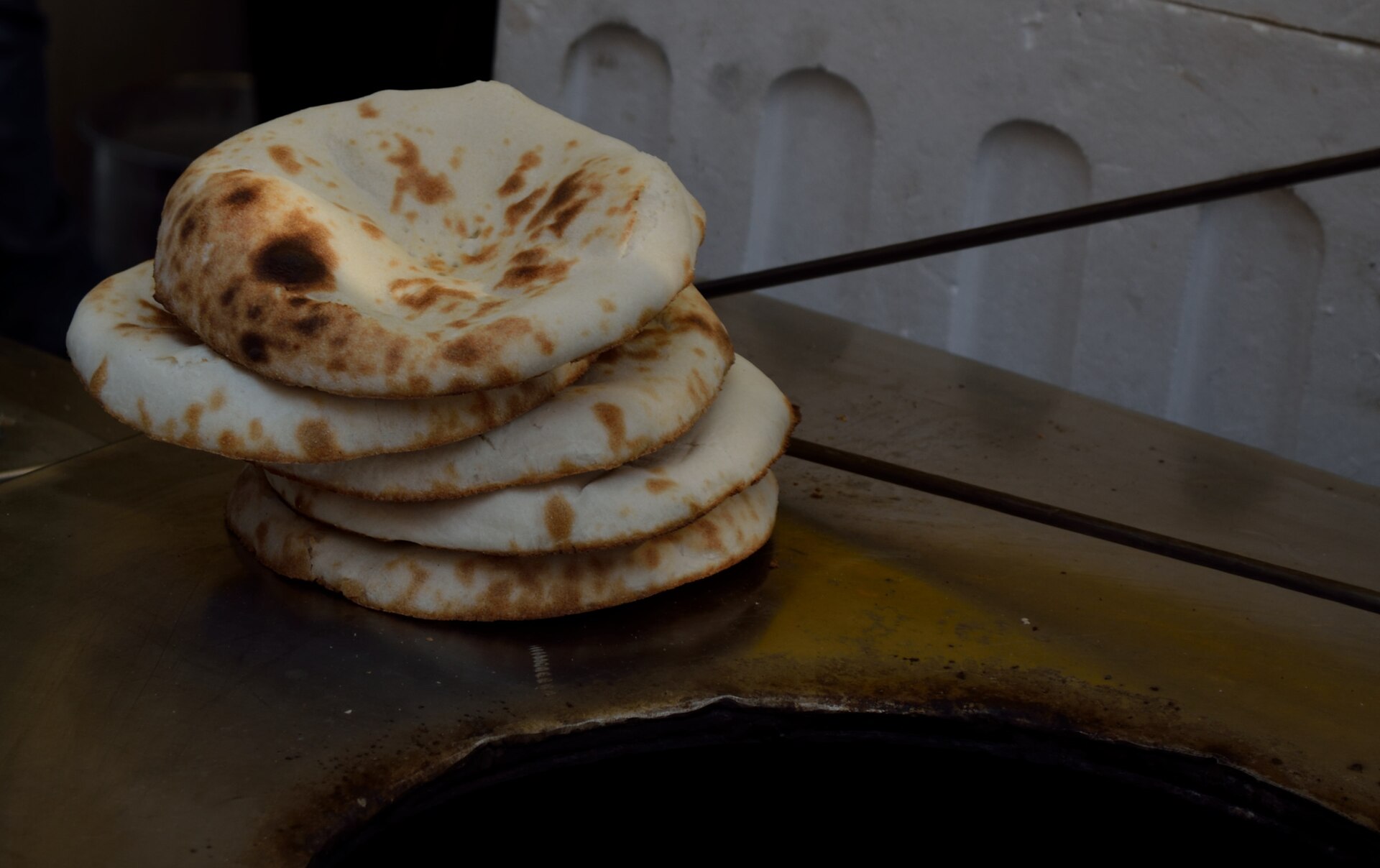 Punjab's Tandoor | The India Freshly made pita bread sits on a steel surface, showcasing traditional Indian cuisine.