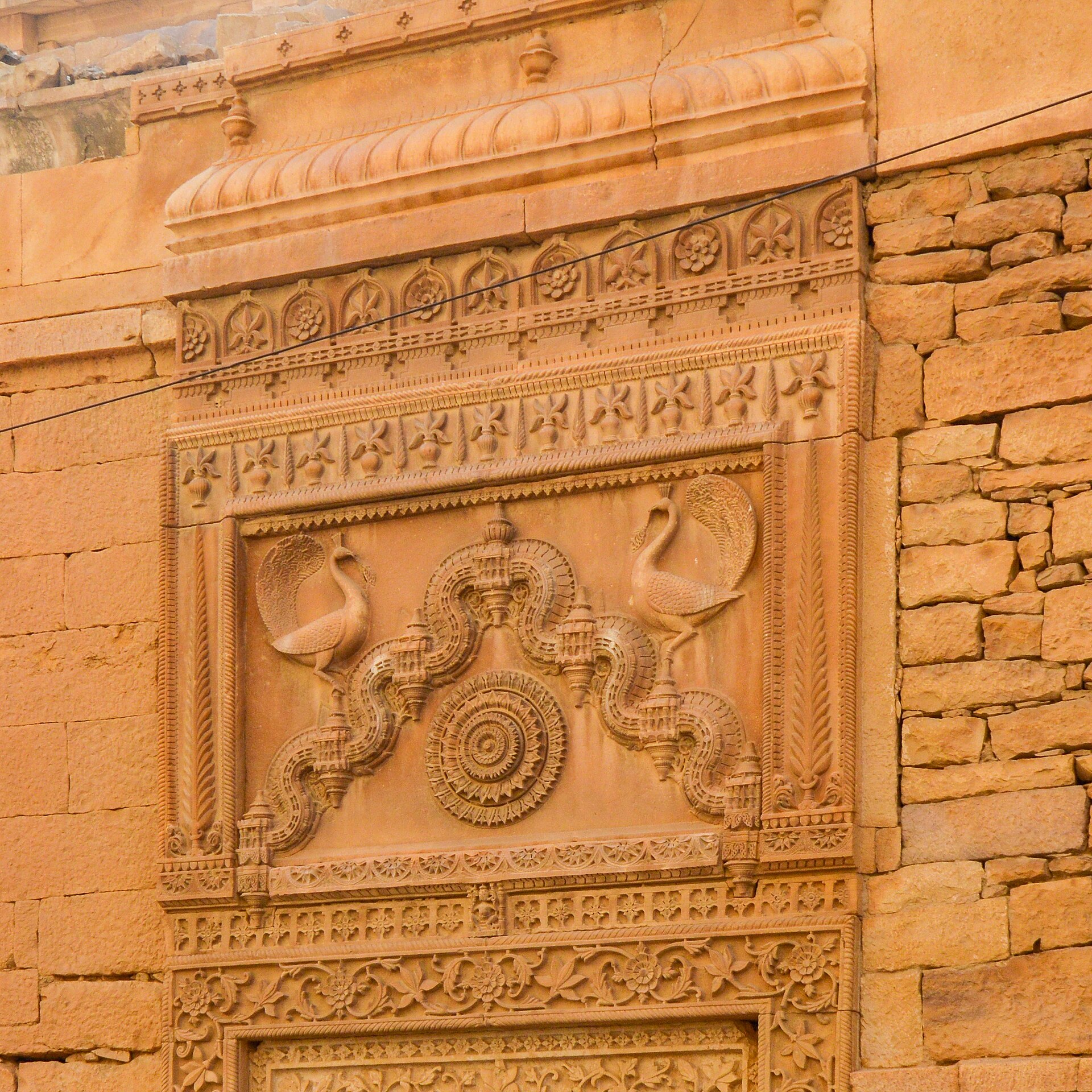 Rajasthan's Desert Circuit | The India Detailed sandstone carving shows birds and a circular motif at Jaisalmer Fort in Rajasthan, highlighting Indian architecture.