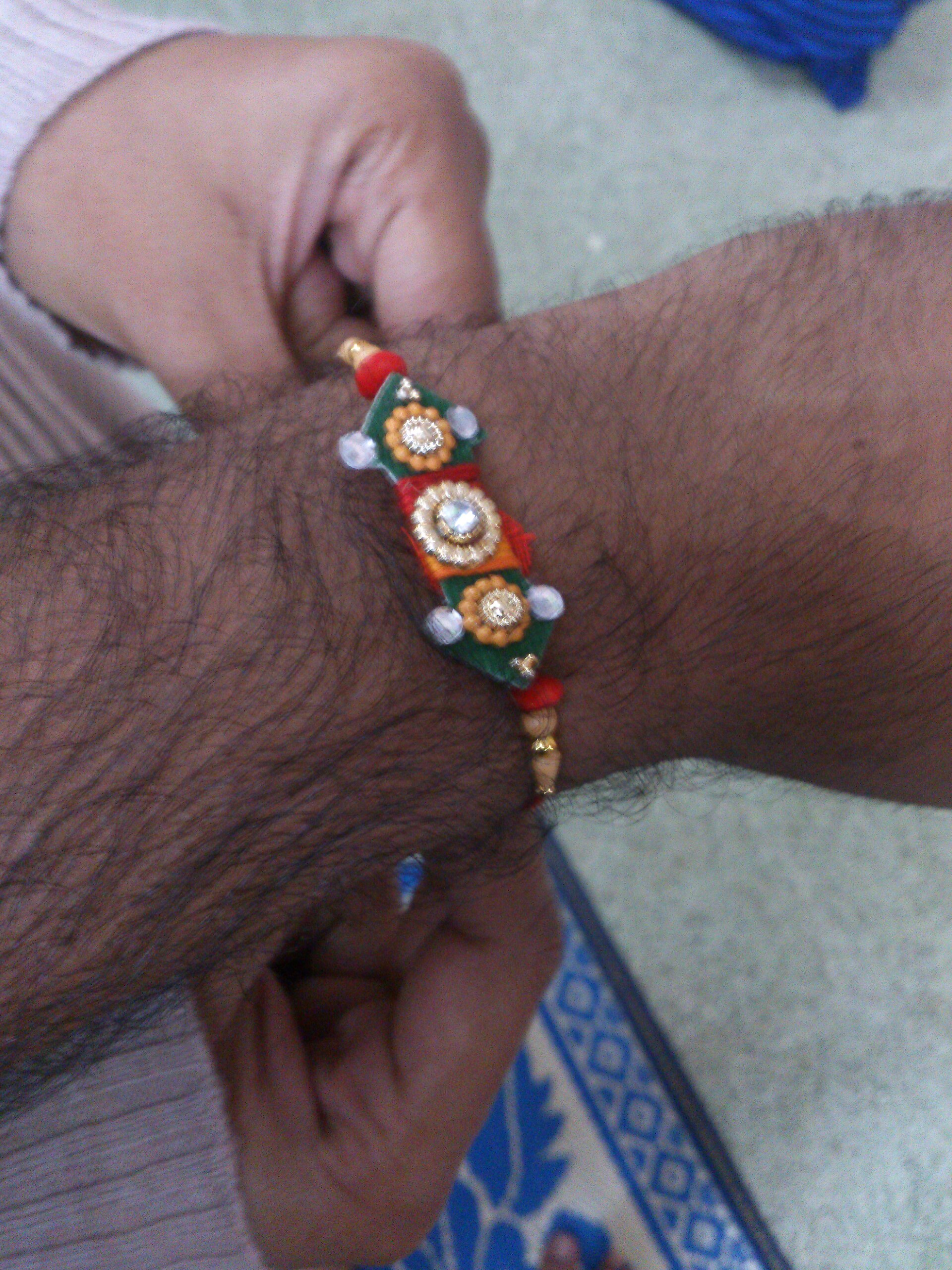 A man’s wrist displays a colorful Rakhi bracelet during the Indian Raksha Bandhan festival.